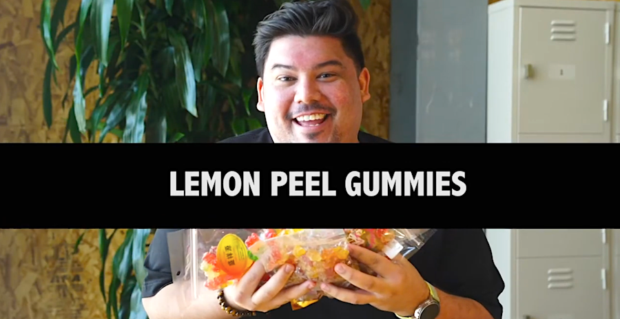 a smiling man holds bagfuls of colorful lemon peel gummy bears