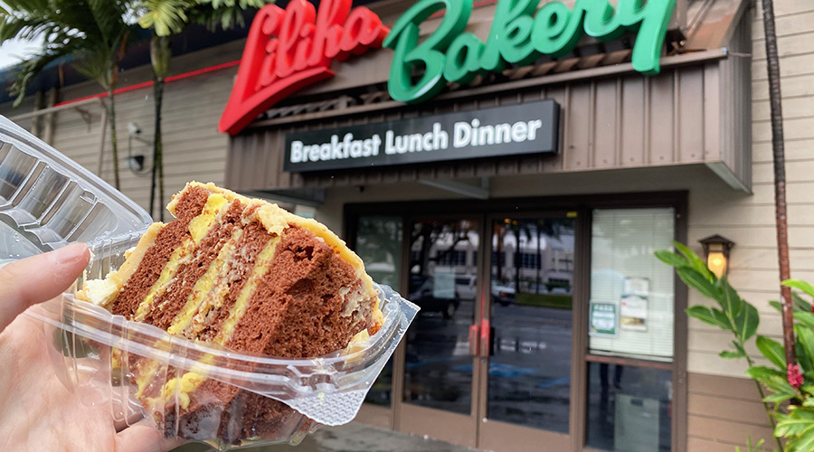 a large piece of dobash and chantilly cake in a takeout container in front of liliha bakery