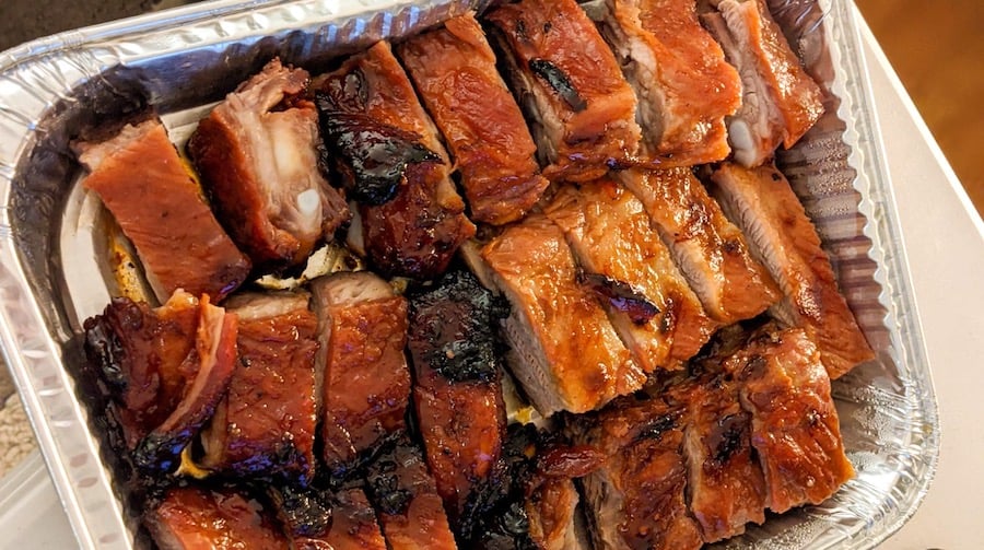 red-lacquered chinese pork ribs are arrayed in an aluminum tray
