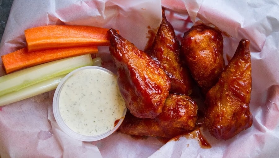 glossy vegan chicken wings in a basket with ranch dressing and celery spears