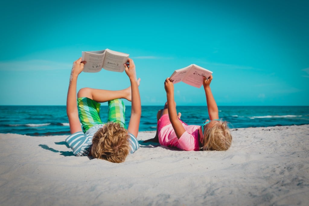 Boy And Girl Reading Books At Beach Vacation