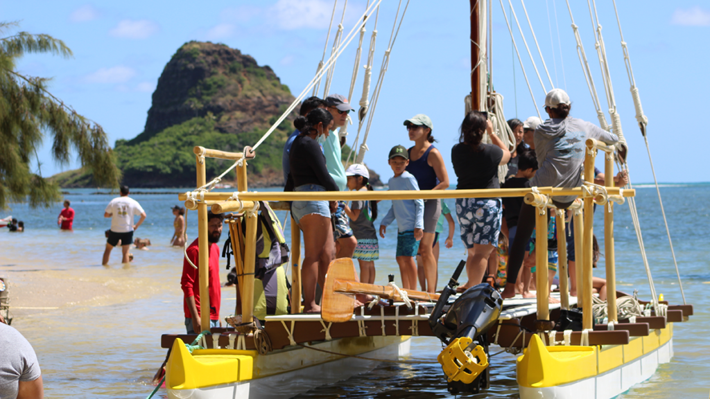 14th Annual Kualoa Hakipu‘u Canoe Festival; a bright yellow boat heading to Chinaman's Hat full of young people