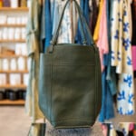 leather handbag in front of clothing rack