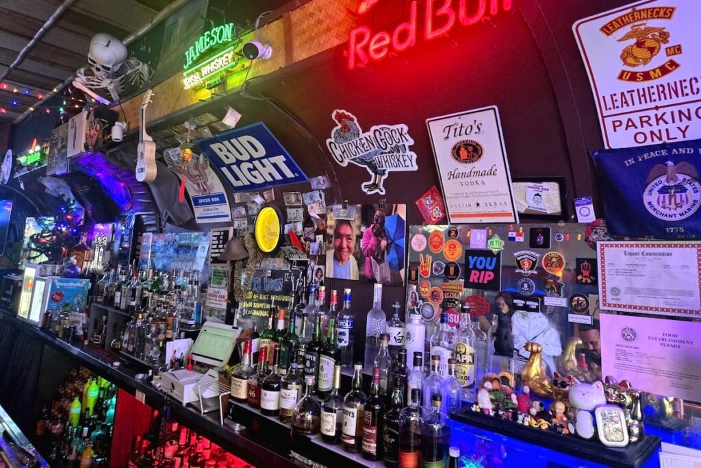 bottles and signs crowd a bar