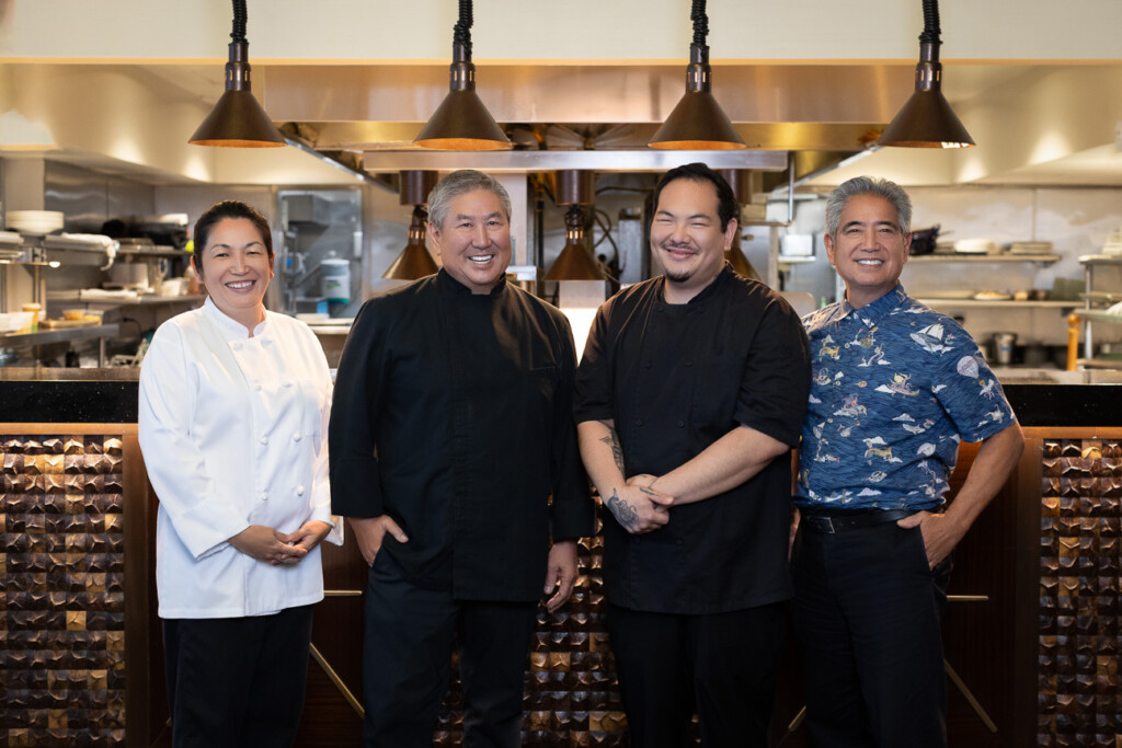 Four people standing in front of a restaurant kitchen