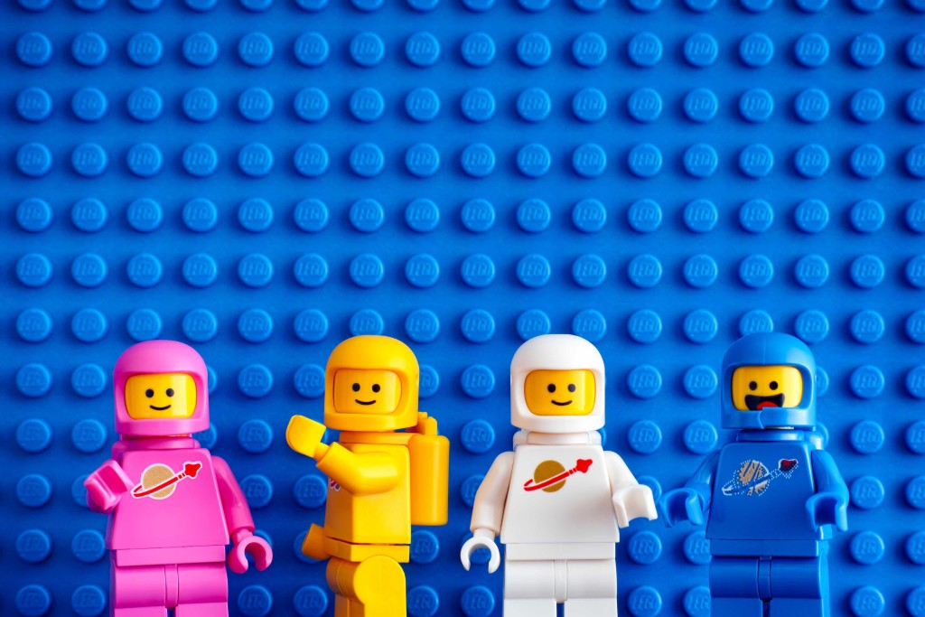 Four Lego Astronaut Minifigures Against Blue Baseplate Backgroun