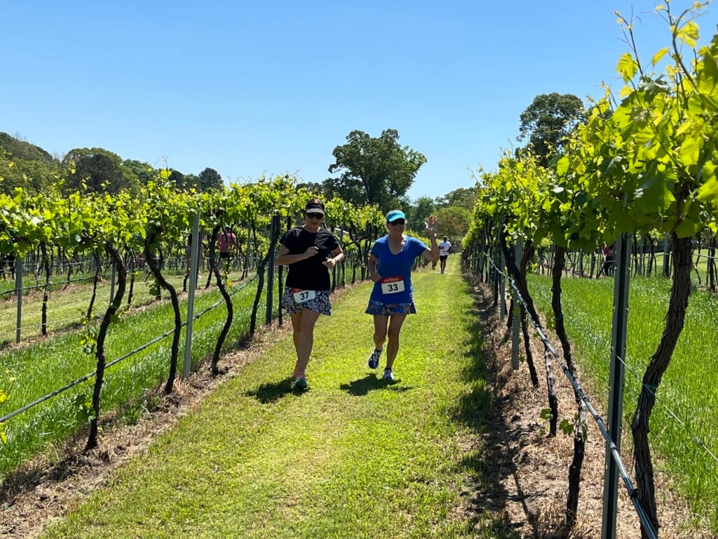 Two women running in vineyard at Landry Vineyards during the April 2025 5k Wine Run