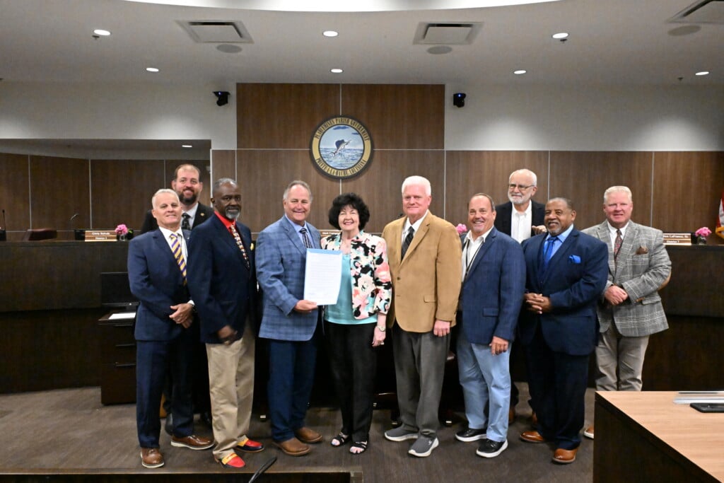 Plaquemines Parish Council poses for photo with Parish President holding piece of paper for the official recognization of Peggy Martin Rose as the parish flower