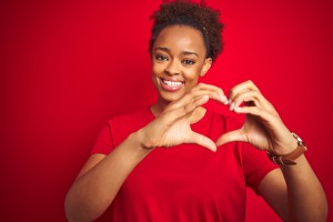 Young Beautiful African American Woman With Afro Hair Over Isolated Red Background Smiling In Love Doing Heart Symbol Shape With Hands. Romantic Concept.