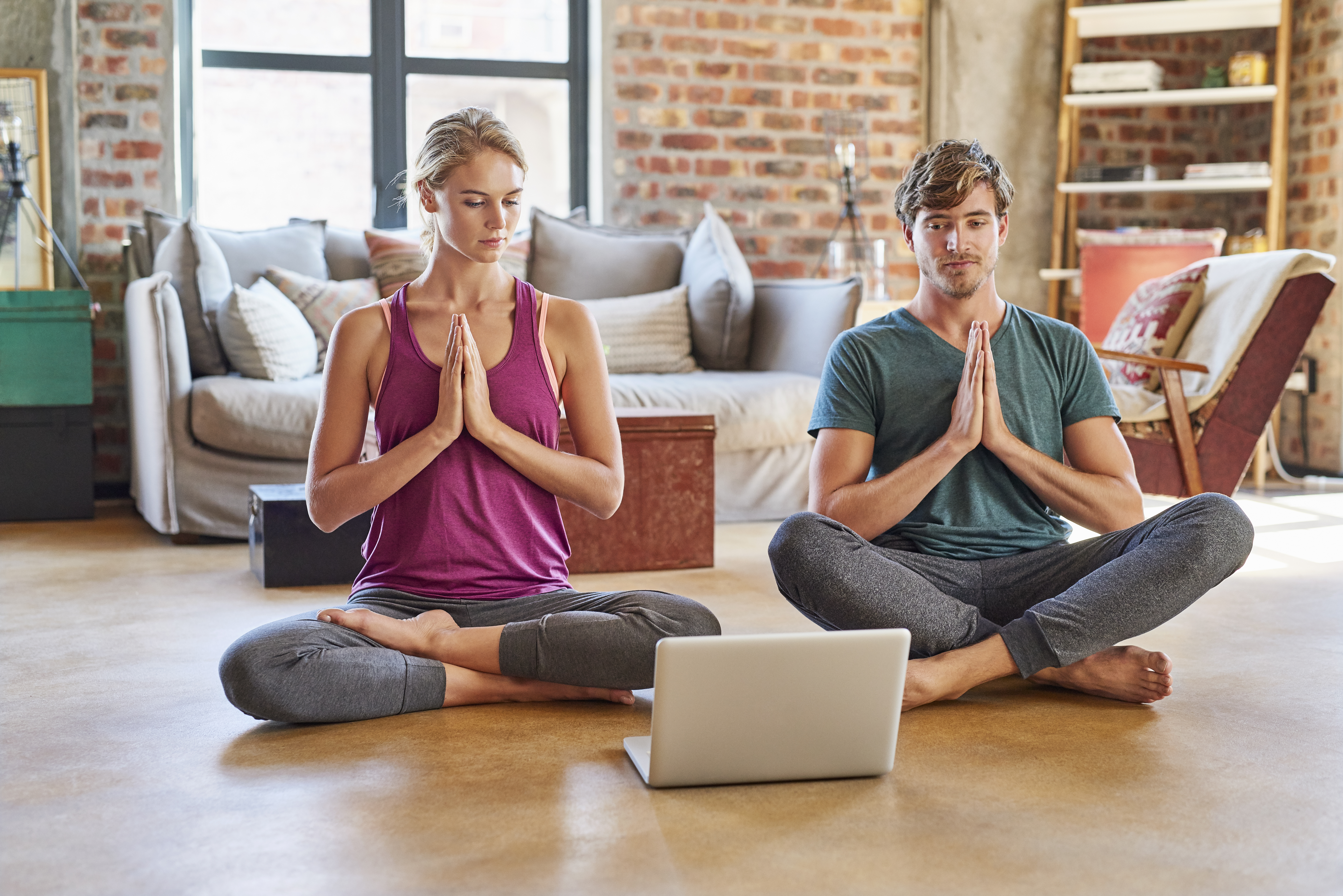 Couple Looking At Laptop While Doing Yoga At Home