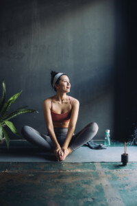 Asian Woman Sitting On An Exercise Mat And Warming Up For A Yoga Session