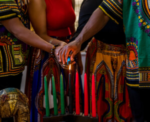 Kwanzaa Celebration, Close Up Of Family Lighting The Kinara Candle In Spirit Of Unity