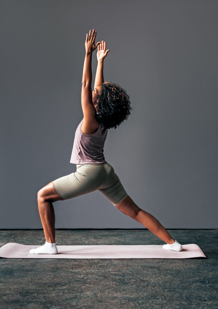 A Beautiful Woman In Sports Clothes Doing Her Daily Workout With Her Arms Raised While Looking Away