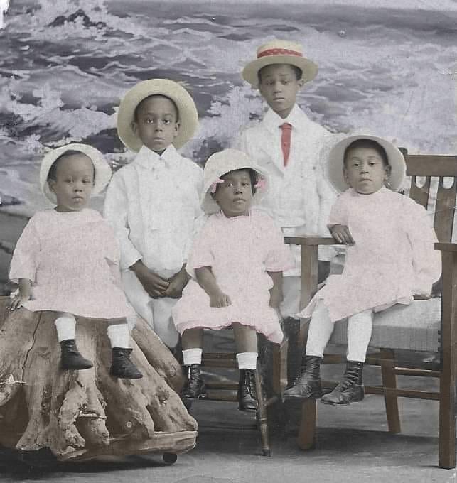 Five children pose for a photograph in Gilded Age-era clothing.