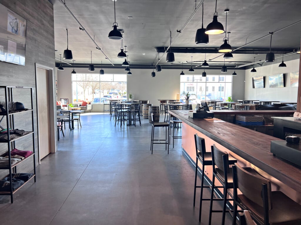 A taproom featuring a wooden bar top and high stools.