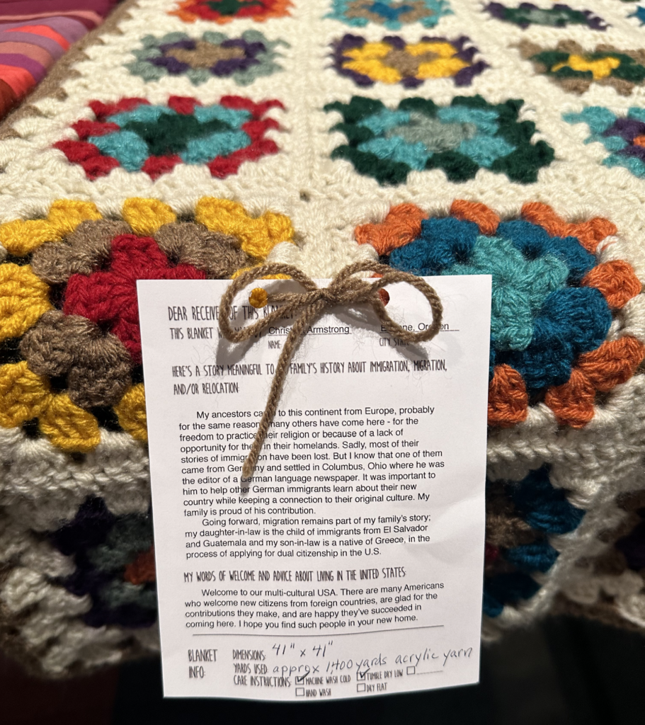A colorful crochet or knit blanket with a note attached.