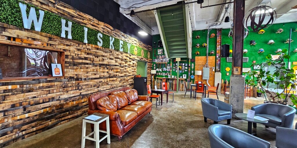 A tasting room featuring couches and the word "whiskey" on one wall, with firemen's hats and other decor on another wall.