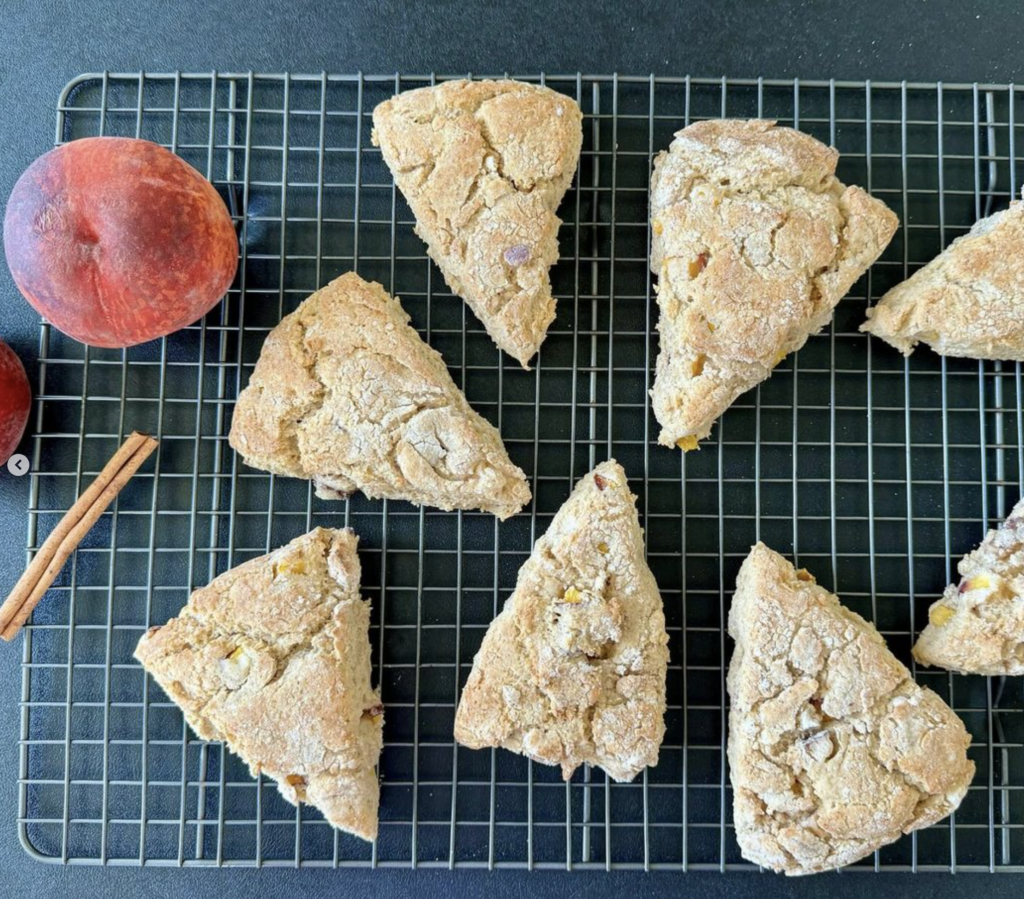 Scones and a peach arranged on a cooling rack.