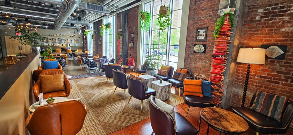 The interior of a sunlit cafe with brick walls and leather chairs for seating.