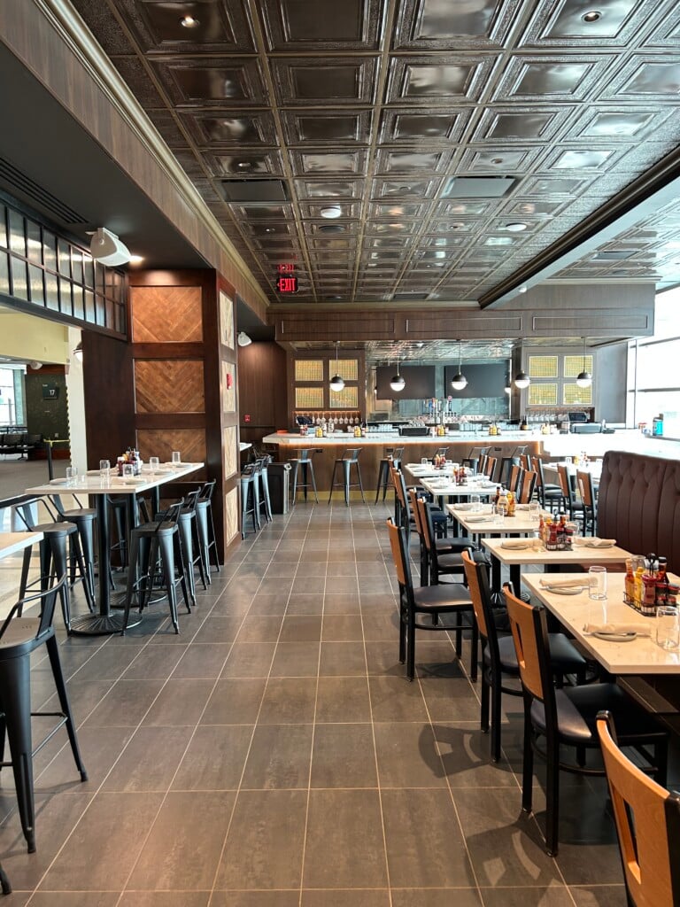 A sleek, empty dining room featuring regular tables and high-tops.