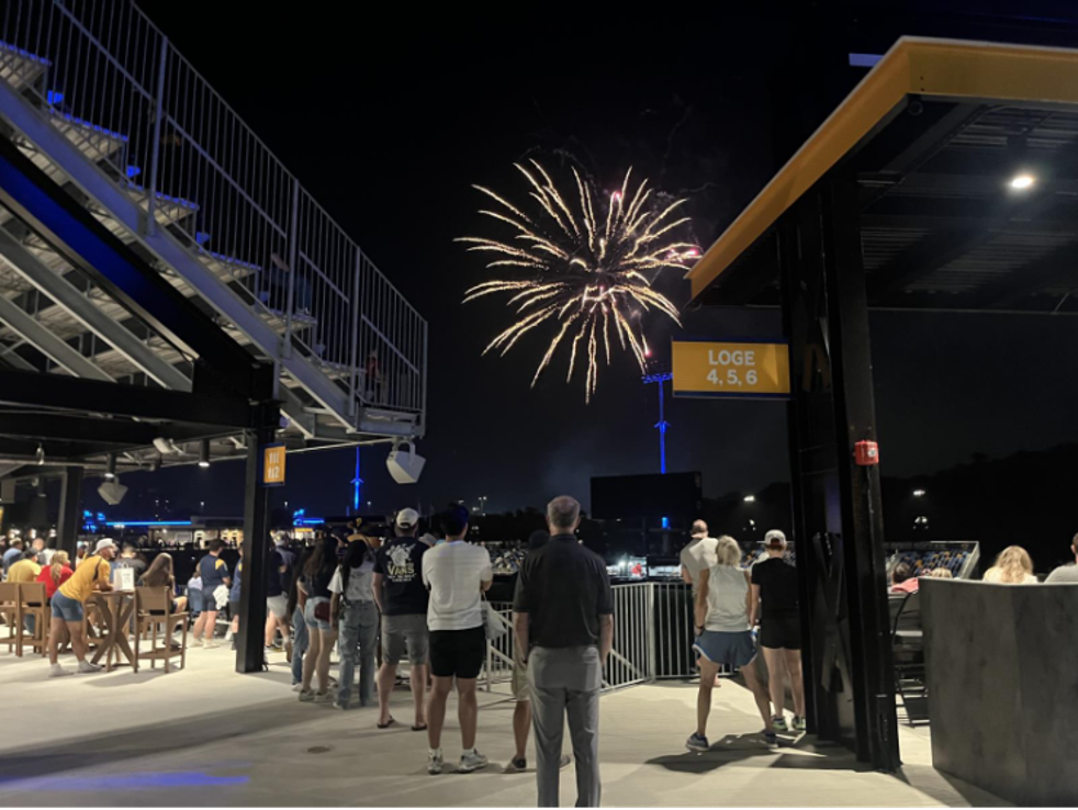 People watch fireworks at night in a stadium.