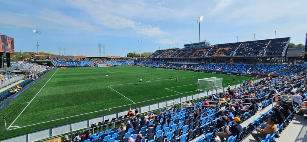 A wide shot of a soccer pitch surrounded by partially filled stands that spell out "RIFC."