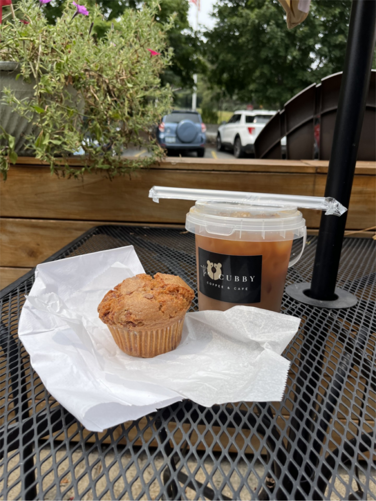 A muffin and a drink on an outdoor table.