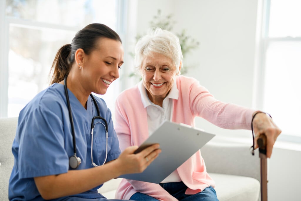 Portrait Of A Young Nurse Doctor With A Senior Patient At Home During A Consultation