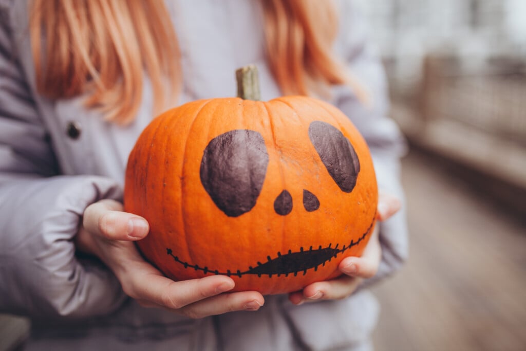 Close Up Of Hand Painted Halloween Pumpkin In Girl's Hands. Diy Halloween Celebrations And Creative Holiday Preparation