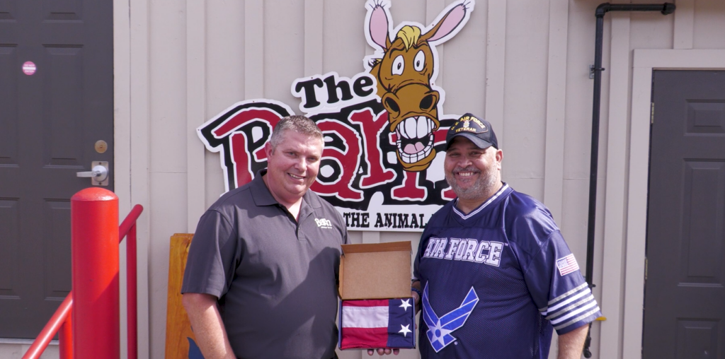 Chadwick Watiker (right) being presented with an American flag made by Annin Flag Company by Jim Watson (left). Watiker is a winner of WHIZ's 6th Annual Military Salute Photo Contest.