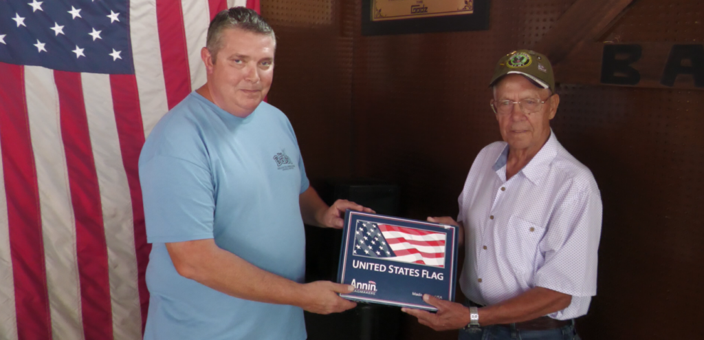 Jim Watson presenting Ellis Dean Kelley a flag as part of WHIZ's Military Salute.